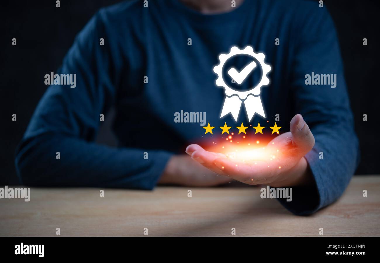 Hand holding a glowing five-star quality assurance badge with a checkmark. Represents excellence and certification. Perfect for quality control, custo Stock Photo