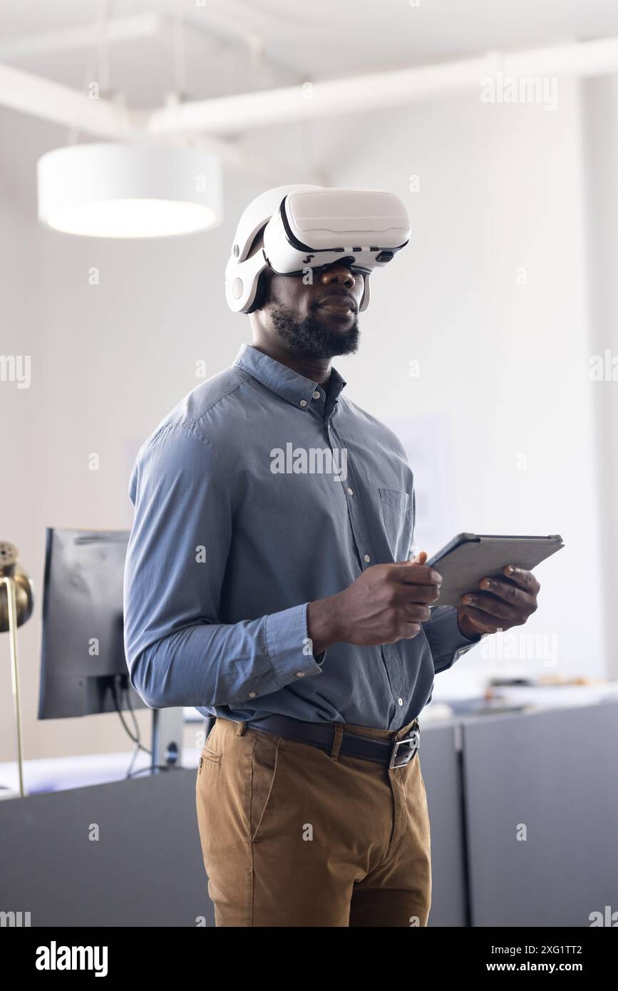 Using VR headset, businessman holding tablet and exploring virtual reality in office Stock Photo