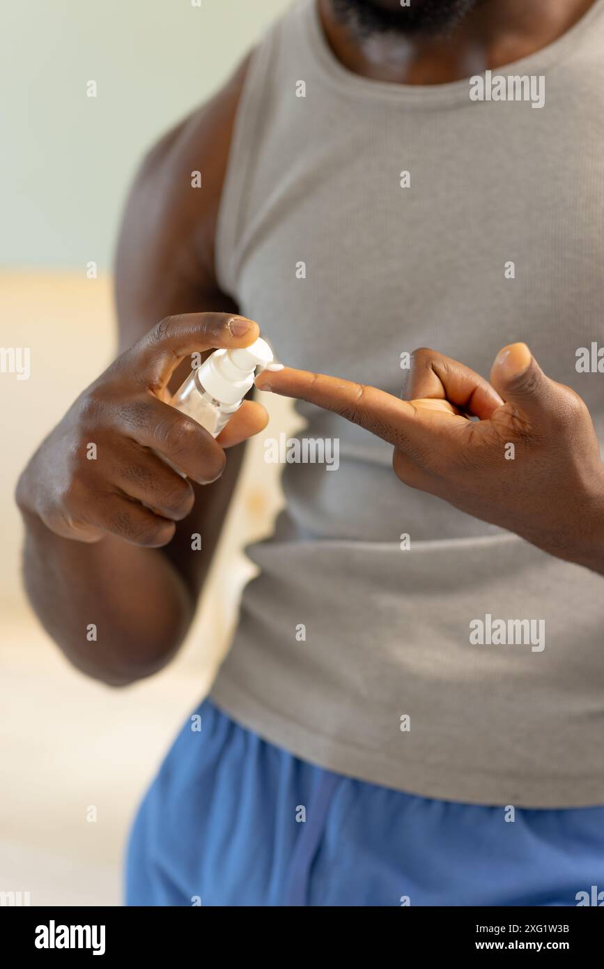 Applying lotion, man using skincare product at home for self-care routine Stock Photo