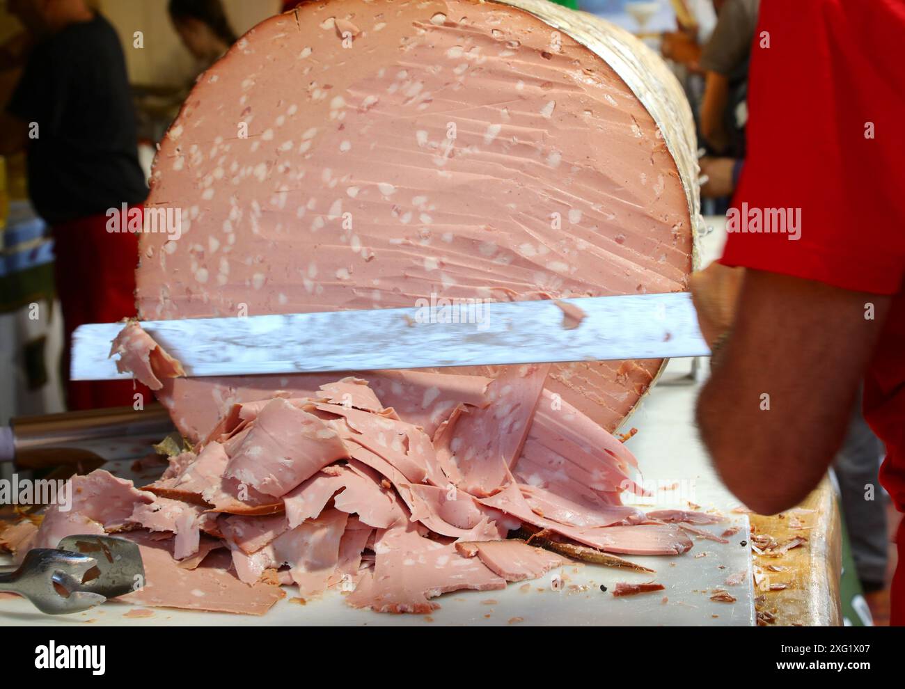chef with a knife slicing a gigantic sausage called MORTADELLA GIGANTE