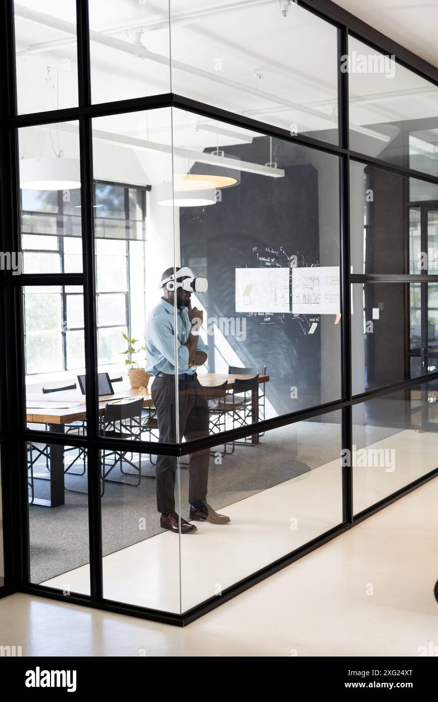 Using VR headset, businessman exploring virtual environment in modern office, copy space Stock Photo