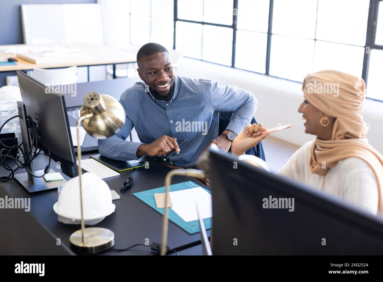 Collaborating at work, colleagues discussing project at office desk with computers Stock Photo