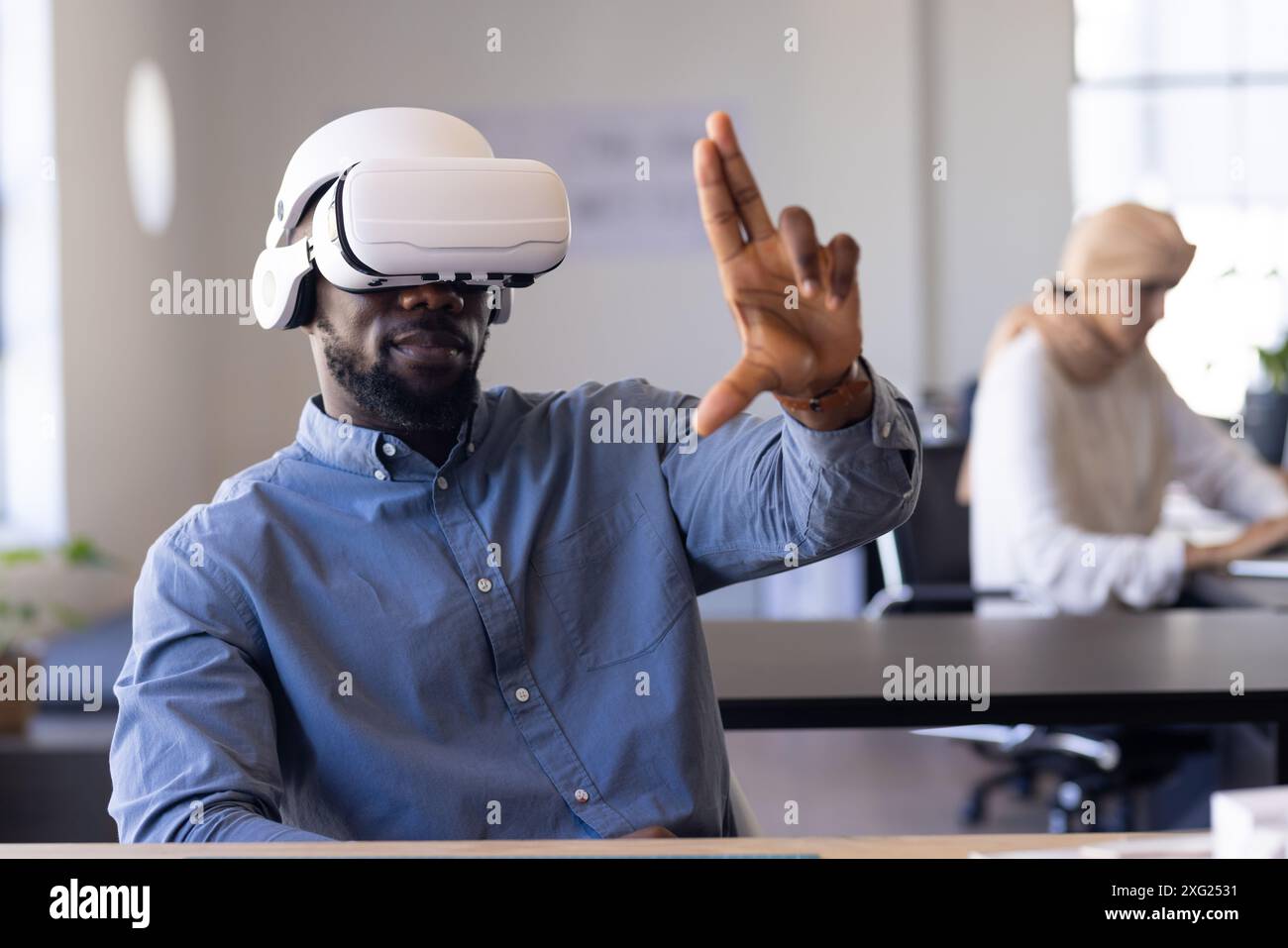 Using VR headset, man interacting with virtual interface in modern office Stock Photo