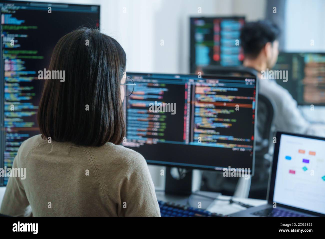 Asian software developers working on multiple screens displaying code ...