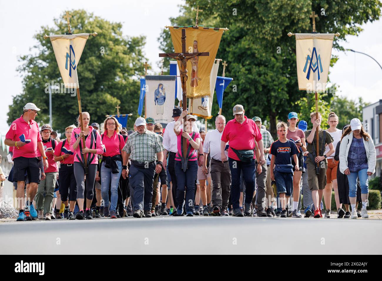 Glandorf, Germany. 06th July, 2024. Pilgrims on the Telgte pilgrimage walk on a road. Around 40 kilometers of country road lie between the episcopal city of Osnabrück in Lower Saxony and the Münsterland pilgrimage site of Telgte. Thousands of believers from the dioceses of Münster and Osnabrück and other regions travel this route on foot to make the Osnabrück pilgrimage to Telgte. In 1852, devout Catholics from Osnabrück made the journey for the first time - this year marks the 172nd anniversary of the festival of faith. Credit: Friso Gentsch/dpa/Alamy Live News Stock Photo