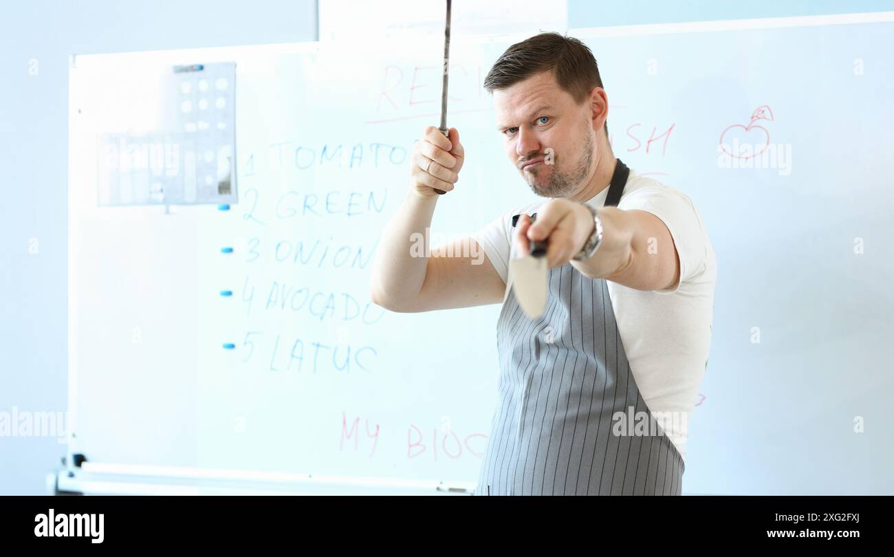 Standing man hold sharp kitchenware for cooking, knife sharpening on kitchen Stock Photo