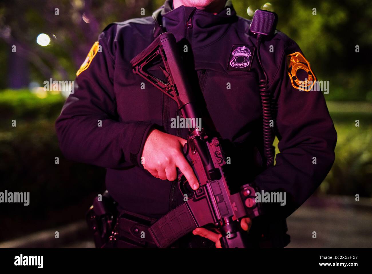 Police officer, night and body of person with gun for law enforcement, protection and responsibility. Neon light, firearm and hands with assault rifle Stock Photo