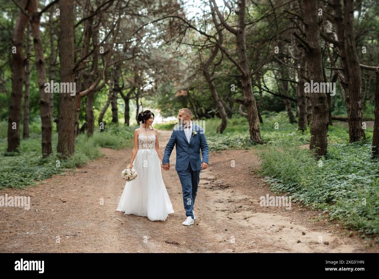 wedding walk of the bride and groom in the deciduous forest in summer ...