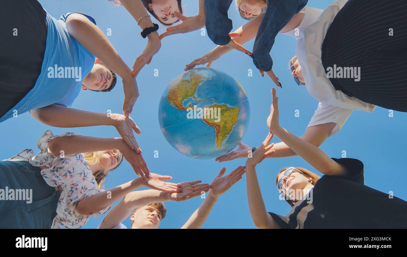 Young friends surround the globe of the world with their palms. The ...