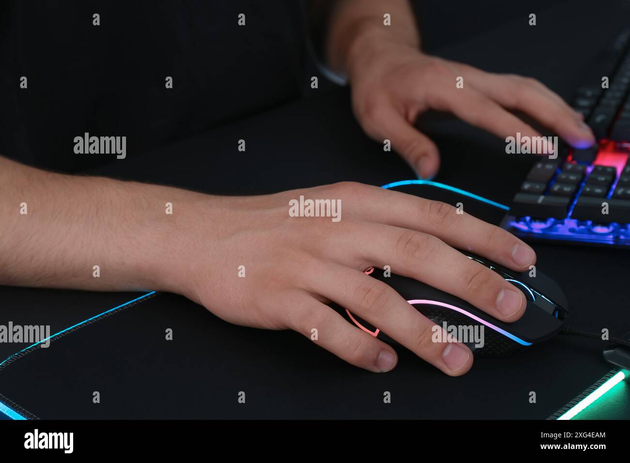 Gamer using modern wired computer mouse at black table, closeup Stock Photo