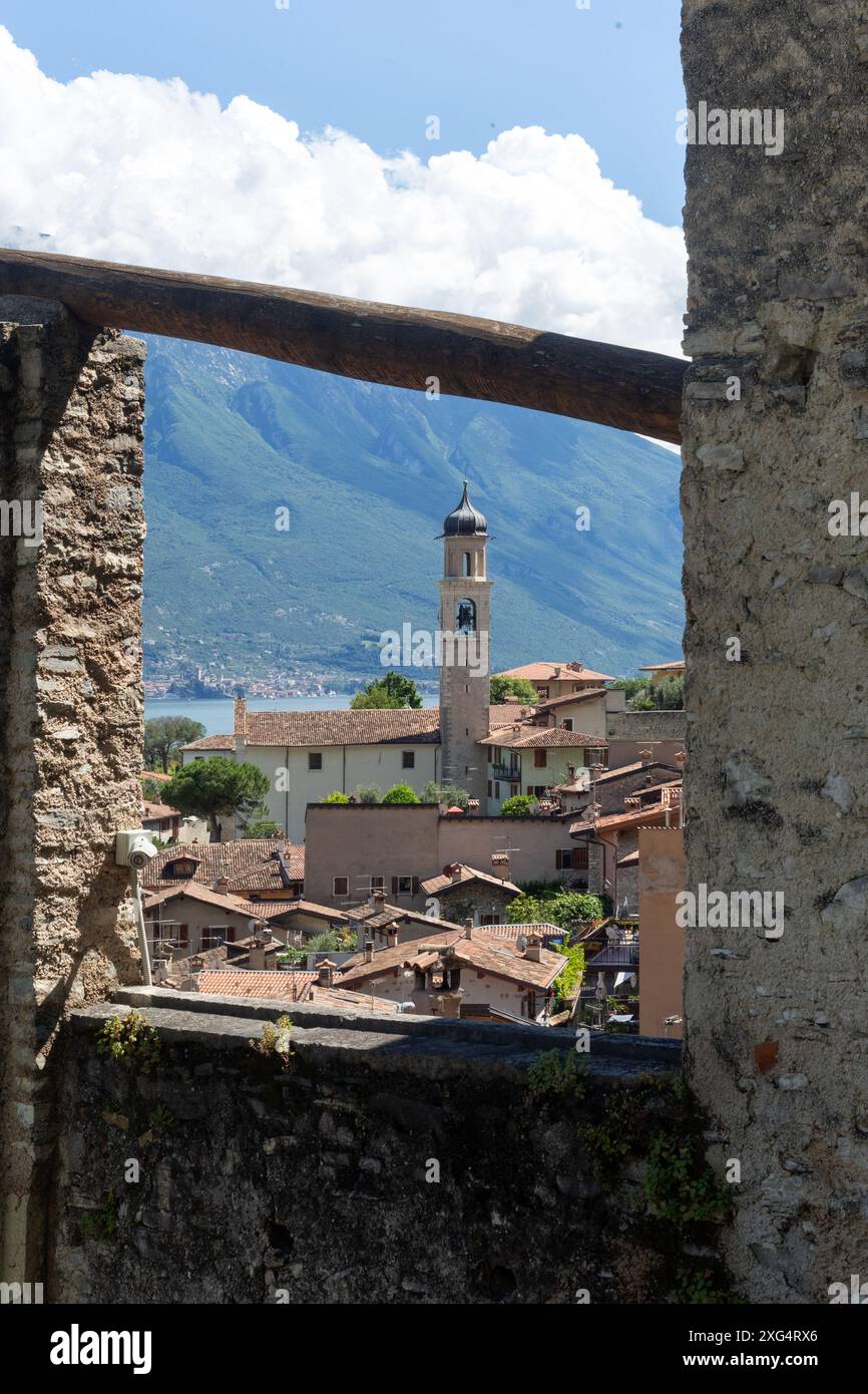 LIMONE SUL GARDA, ITALY - JUNE 13, 2024:  View of the town and tower of the Church of San Benedetto from hillside Lemon Grove Stock Photo