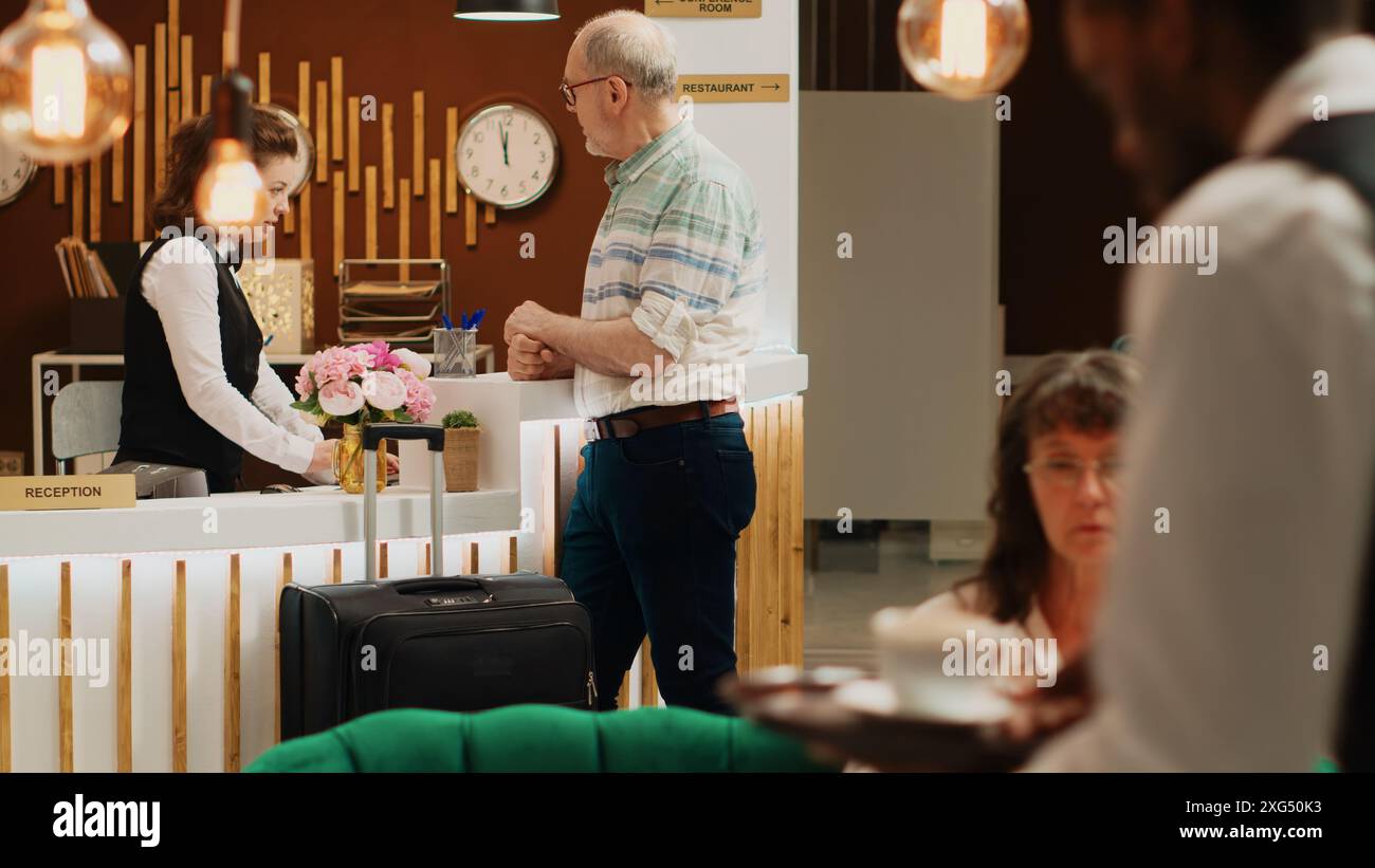 Caucasian man arriving at luxury hotel lobby, goes for check in ...