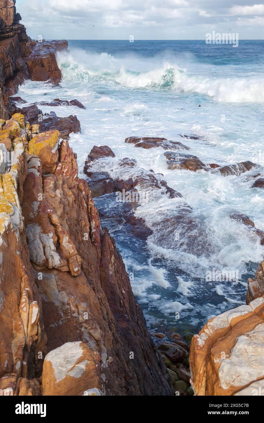 The waves hitting the rocks and orange rocks on the beach in Cape of ...