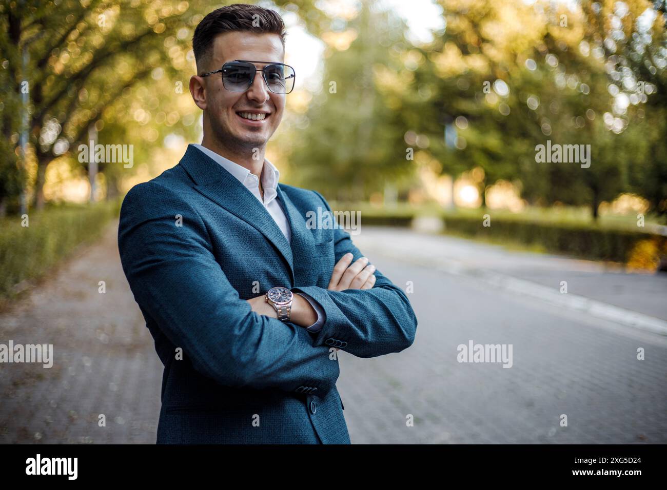 A man dressed in a suit and wearing sunglasses stands on a busy city ...