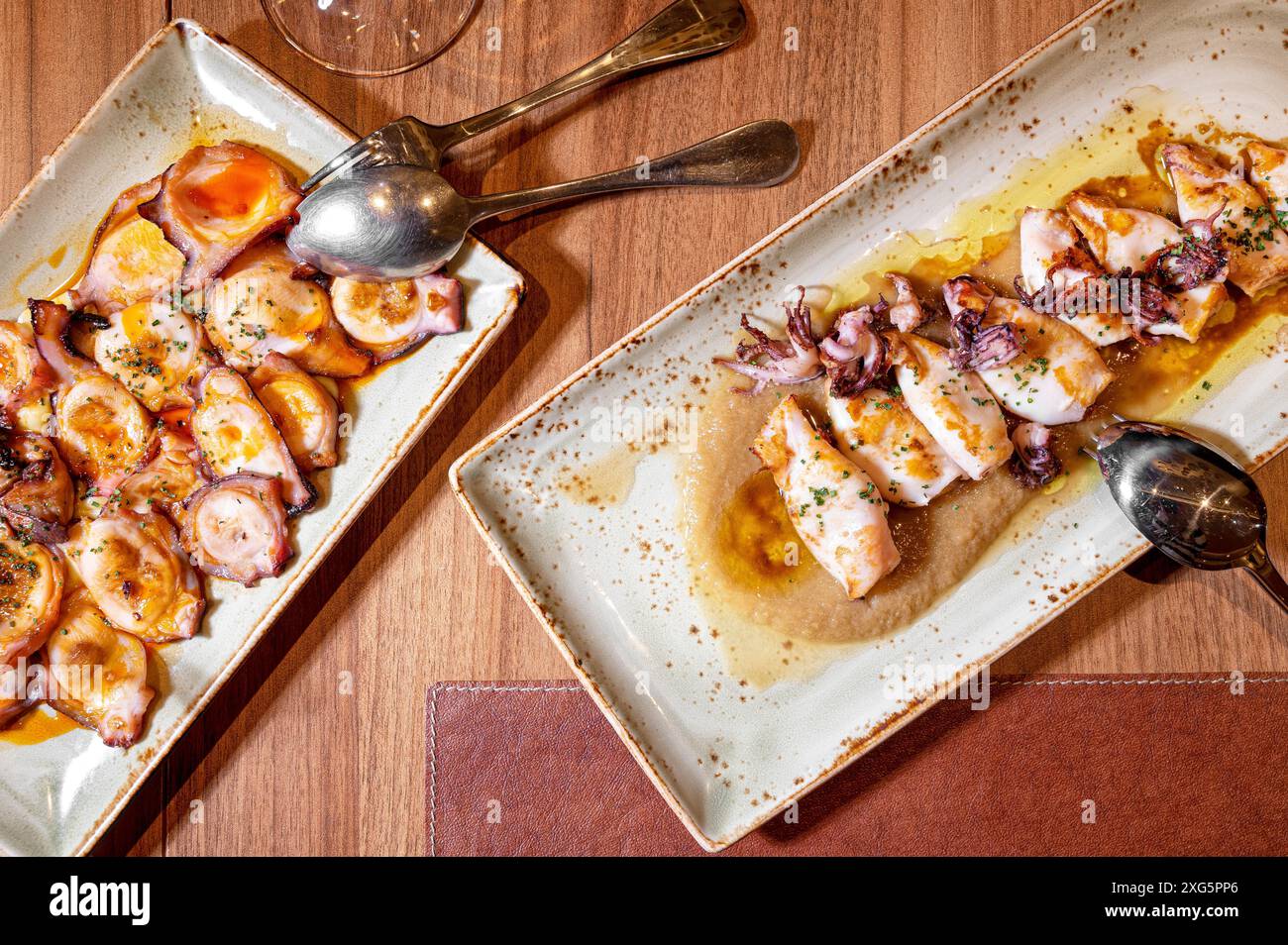 Directly above of a restaurant table with plates of Grilled squid and octopus with olive oil. High quality photography Stock Photo