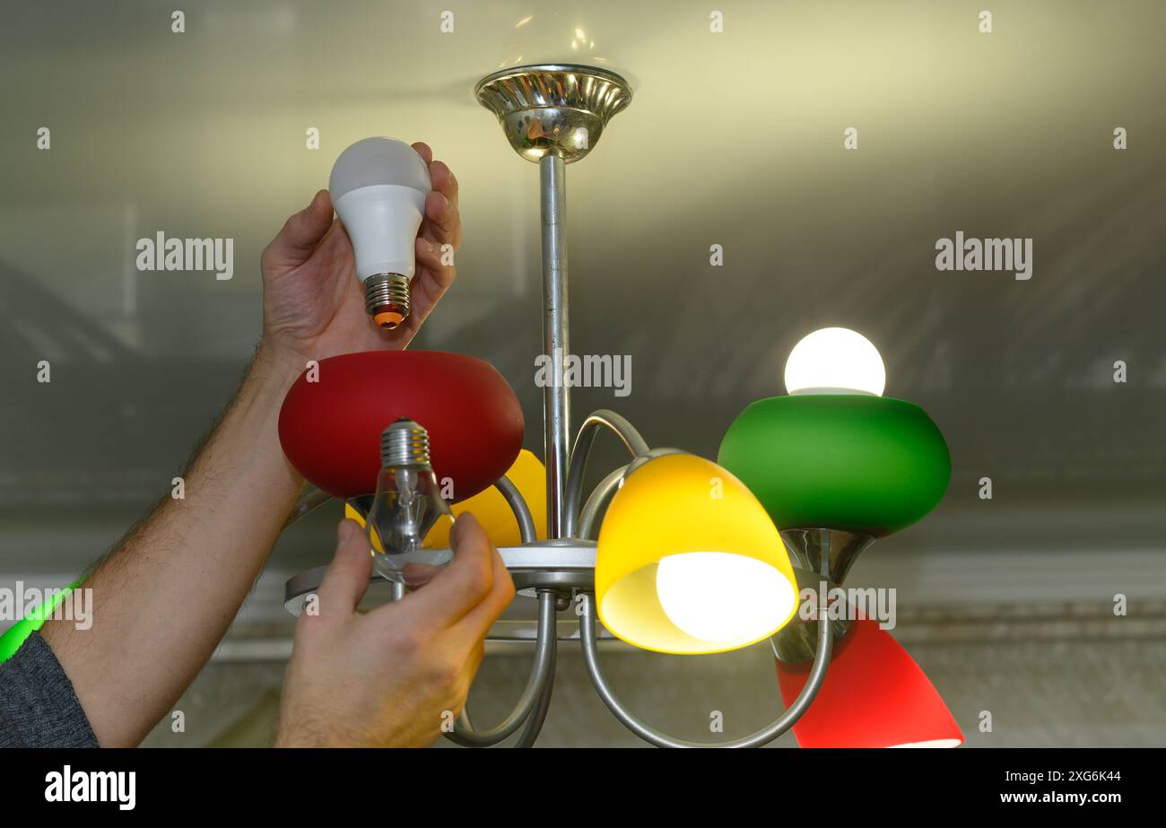 replacing an incandescent light bulb with an energy efficient LED lamp Stock Photo