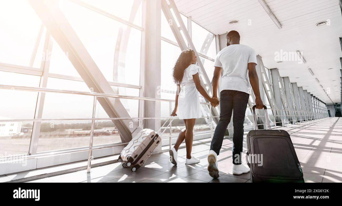 Black Couple Walking Through Airport Terminal With Luggage Stock Photo ...