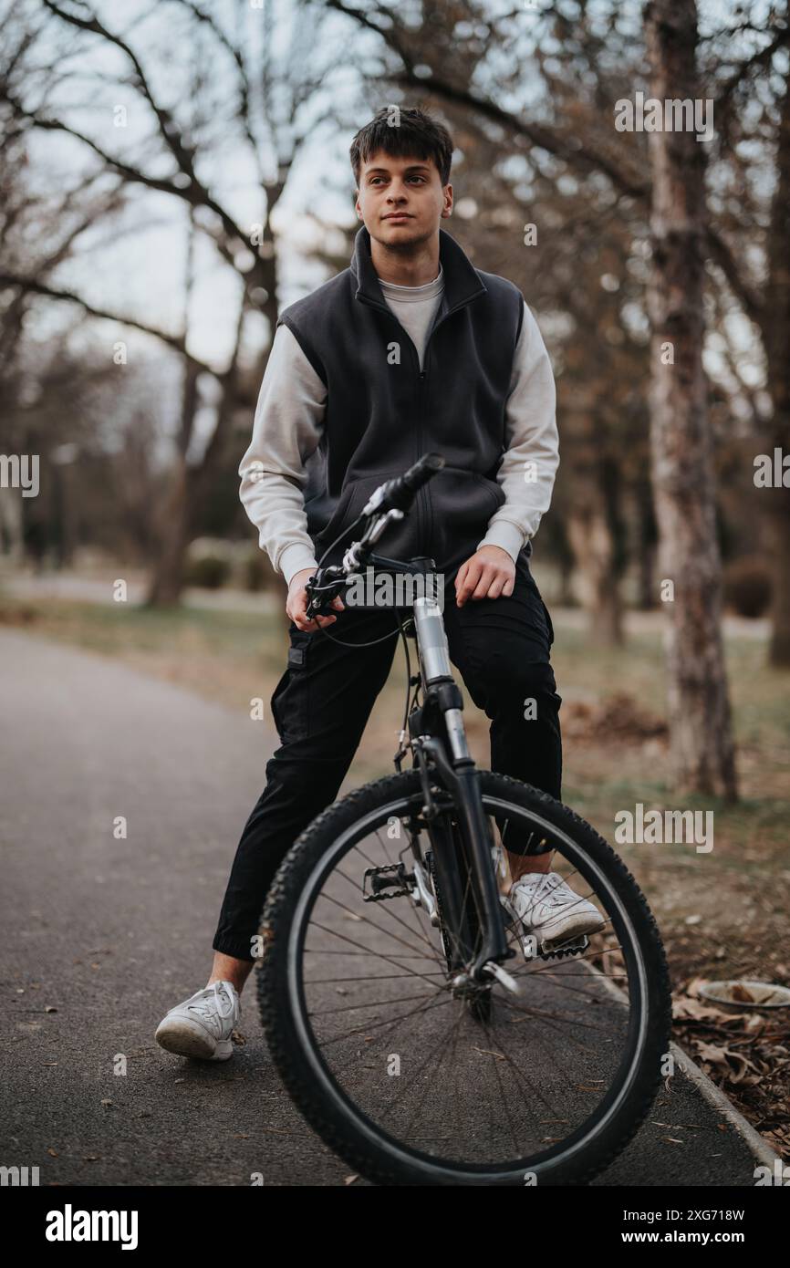 Teenage boy enjoying a leisurely bike ride in a serene park setting ...