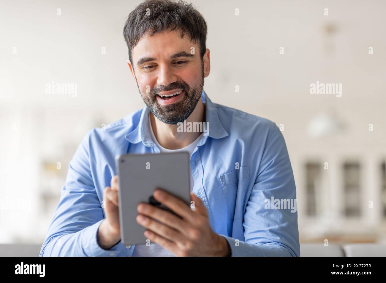 Happy Man Using Tablet in Casual Setting Stock Photo