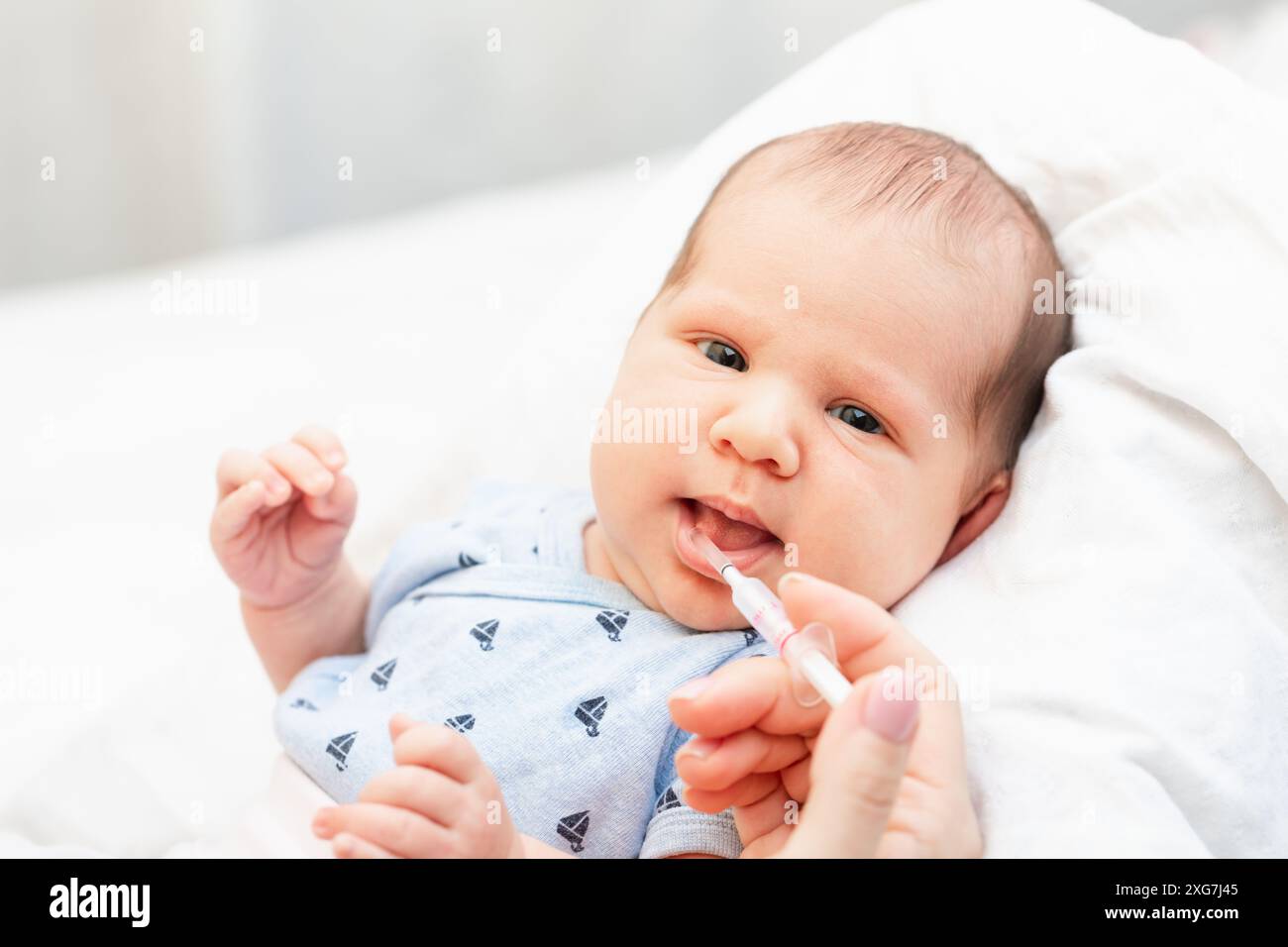 Mother feeding newborn baby with Vitamin K to prevent Vitamin K