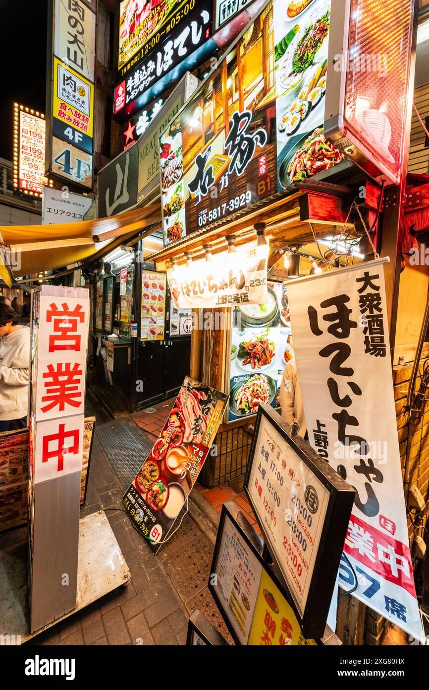 Close up of the cluttered entrances to two Japanese Izakaya restaurants in the popular nightlife Ameyoko Ueno district in Tokyo. Menu boards outside. Stock Photo