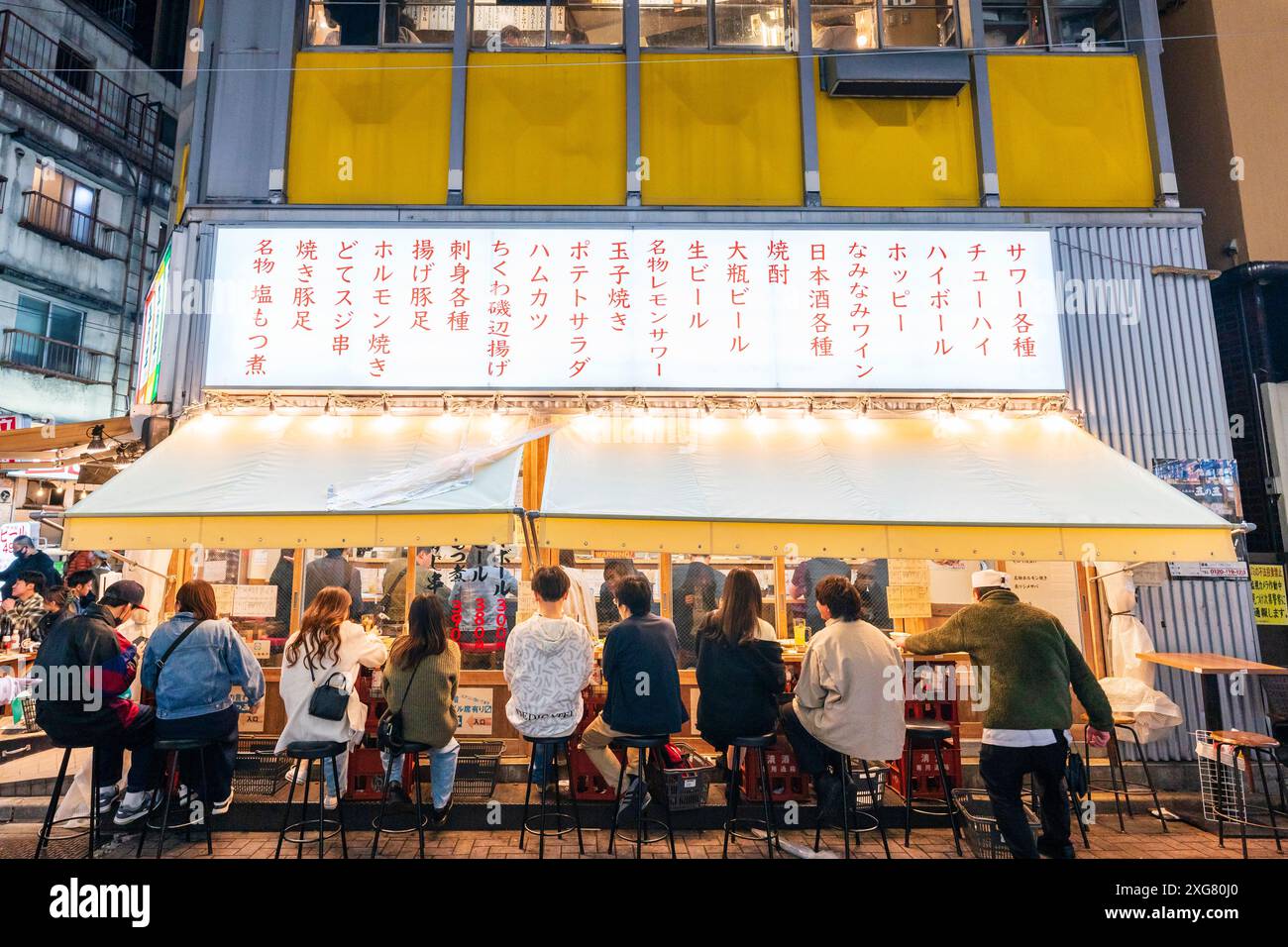 Diners sitting outside a two-story Japanese Izakaya restaurant bar in the popular nightlife district of Ameyoko Ueno in Tokyo. Stock Photo