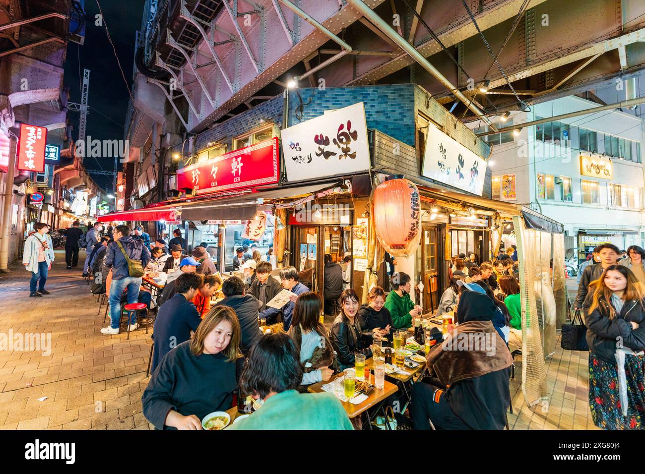 People sitting dining outside the busy Gyukatsu Motomura Ueno tonkatsu ramen restaurant in the popular Ameyoko Ueno nightlife area in Tokyo. Stock Photo