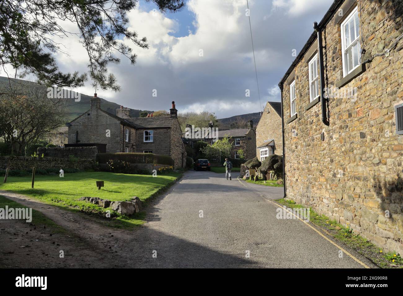A lone walker heads north out of Grindsbrook Edale in Derbyshire Peak District National park England UK English village outdoors Stock Photo