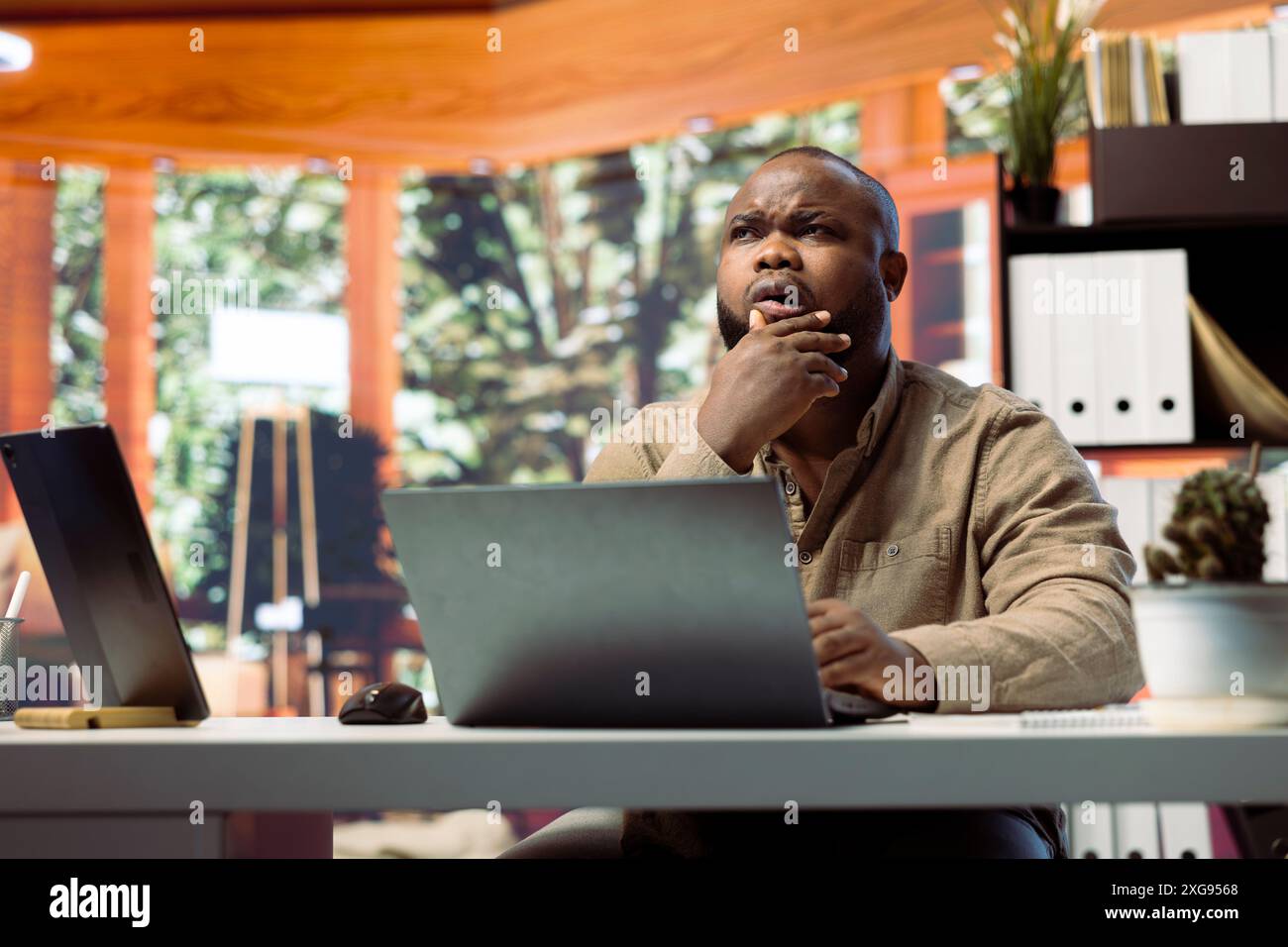 Freelancer managing startup projects and thinking about client needs from his home office, developing new growth strategy. Self employed analyst does telecommuting work on laptop. Stock Photo