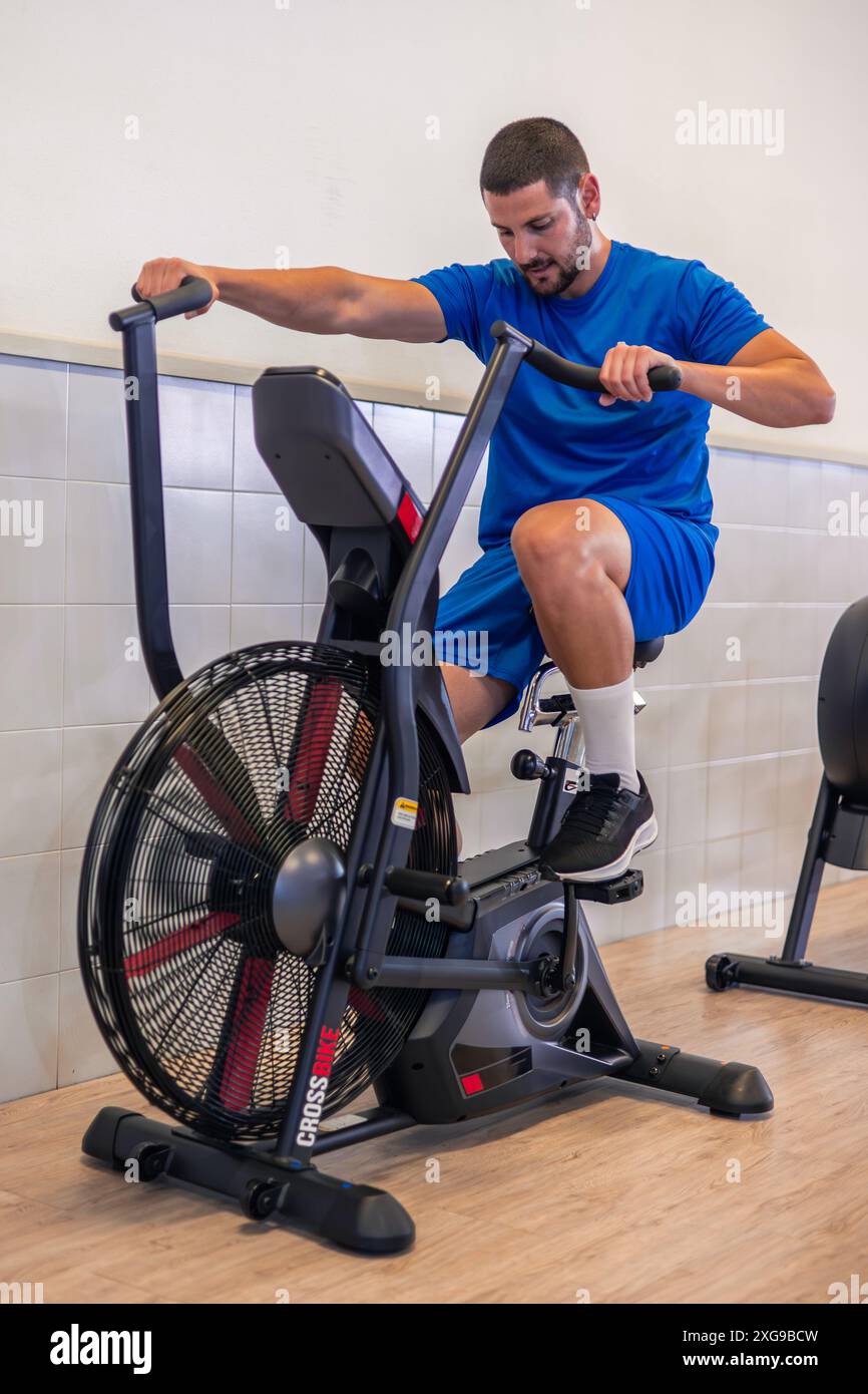 Pindiling Exercise vertical fitness athlete is seen pedaling with effort on an air bike ...