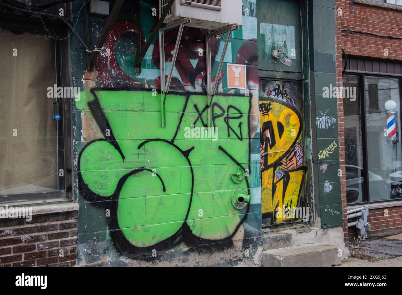 Graffiti tagged on a building beside a barber shop on Saint-Laurent Boulevard in downtown Montreal, Quebec, Canada Stock Photo