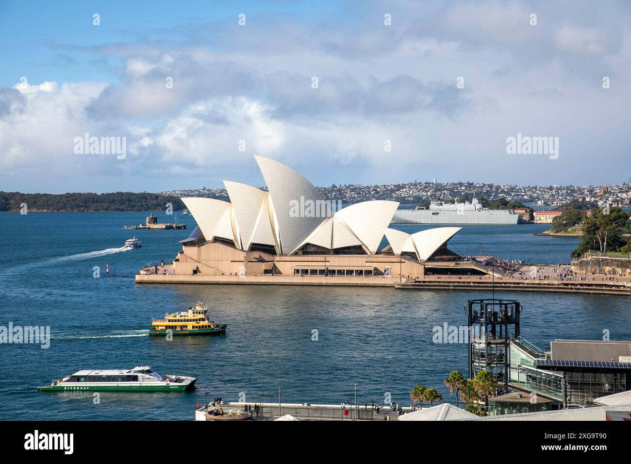 Sydney Opera House and harbour view with Sydney ferry on the harbour and HMAS Canberra at Garden Island naval base, New South Wales,Australia Stock Photo