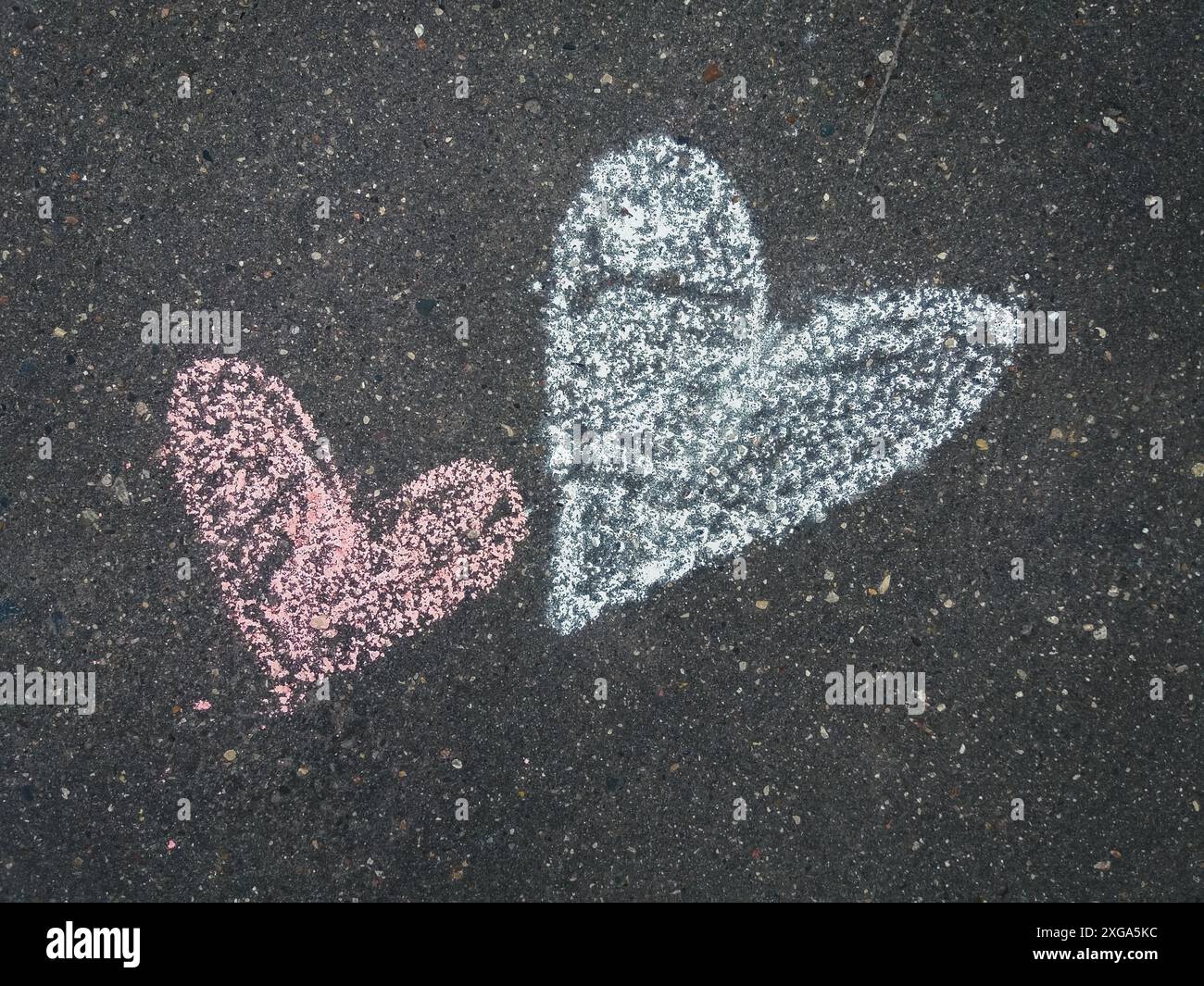 Two chalk drawn hearts on the asphalt, closeup Stock Photo