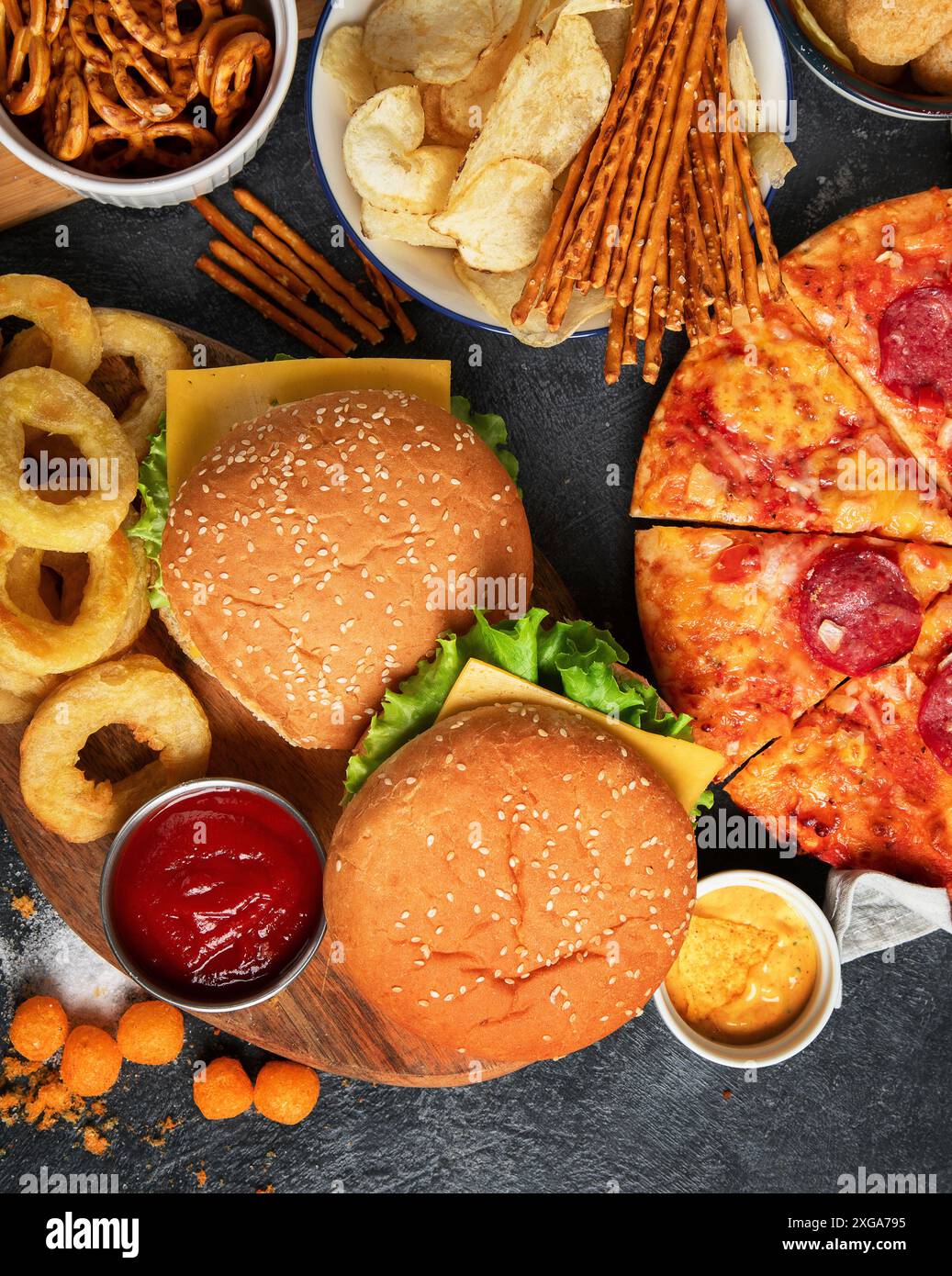 Large table of assorted take out food such as pizza, french fries, onion rings, burgers and