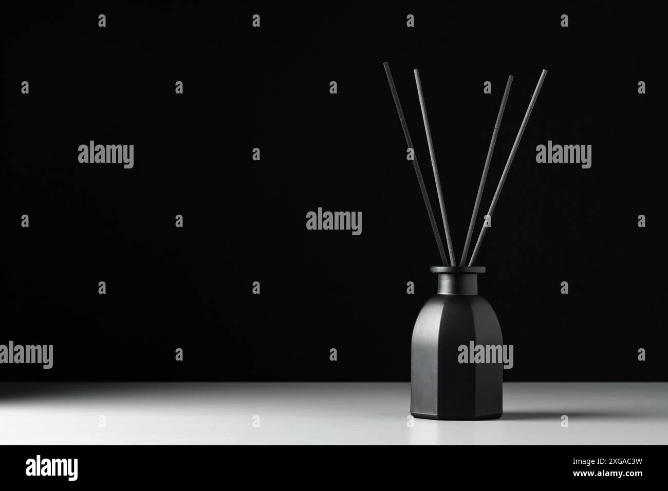 Black Reed Diffuser Bottle On White Surface Against Black Background Stock Photo