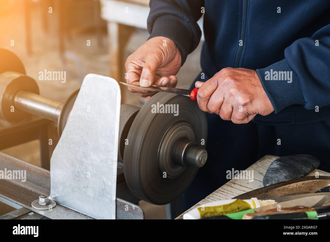 hands of a male sharpener grinder sharpening knife blade on a ...