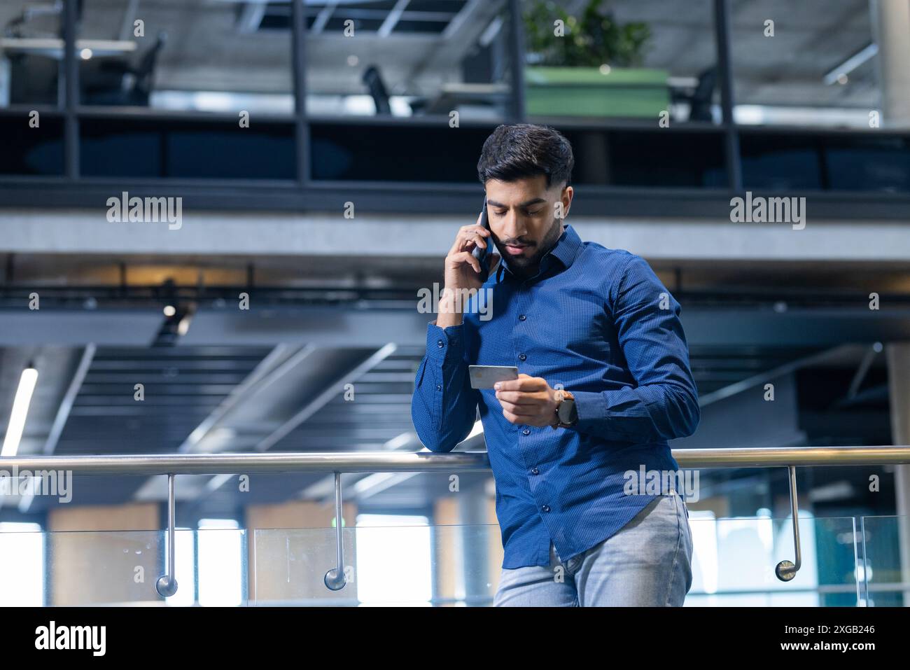 Talking on smartphone, man checking notes in modern office building, copy space Stock Photo