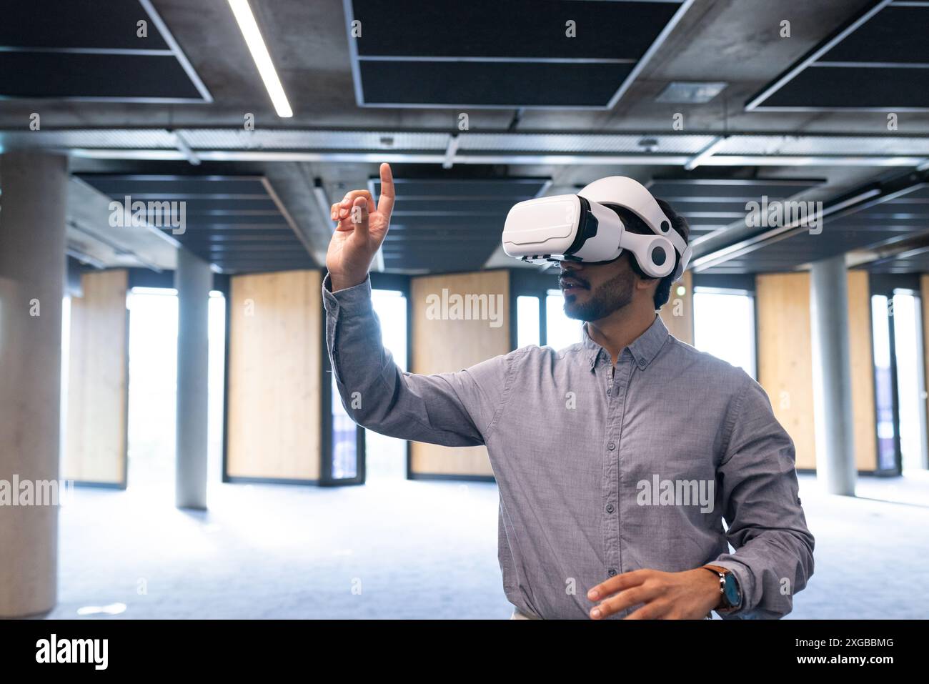 Using VR headset, man interacting with virtual interface in modern office, copy space Stock Photo