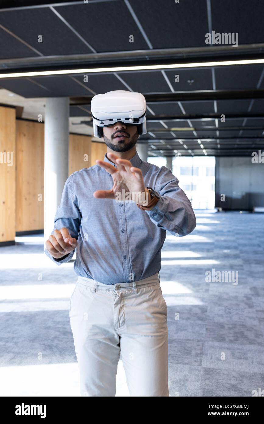 Using VR headset, businessman exploring virtual reality in modern office space Stock Photo