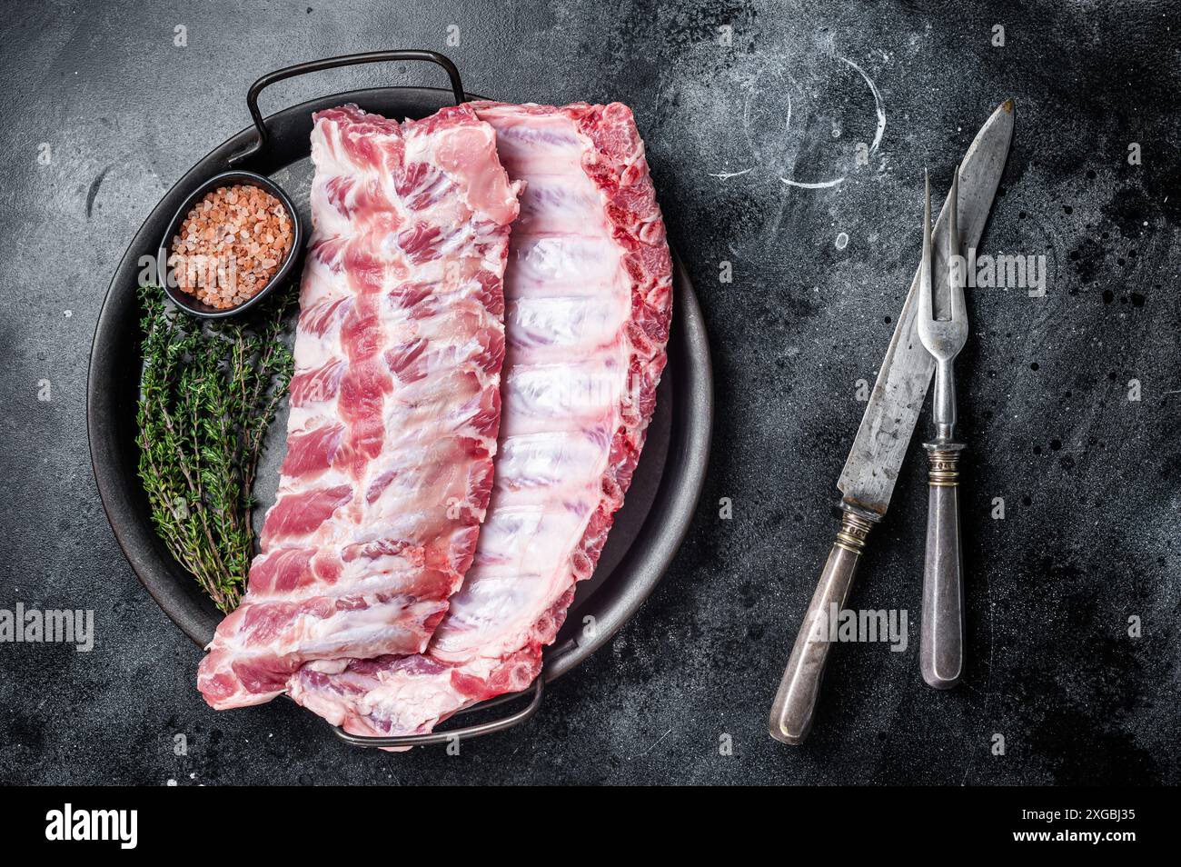 Raw rack of pork spare ribs in steel kitchen tray. Black background ...
