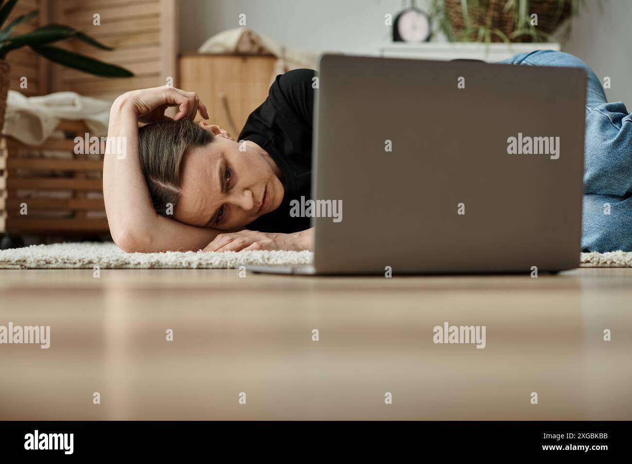 Woman finds comfort with her head on laptop, seeking solace from mental struggles. Stock Photo