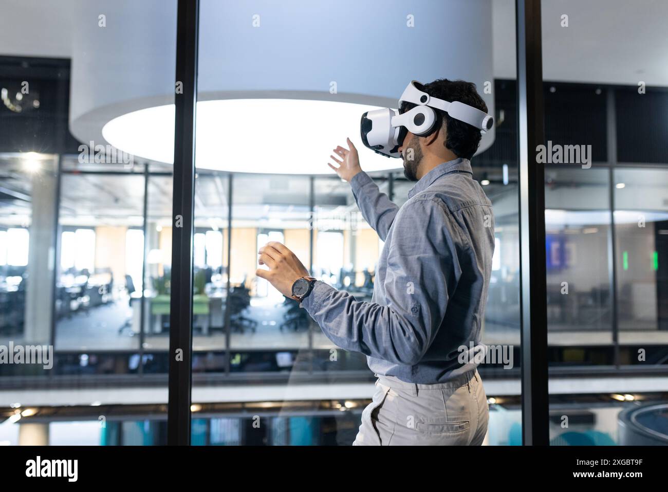 Using VR headset, man interacting with virtual environment in modern office, copy space Stock Photo