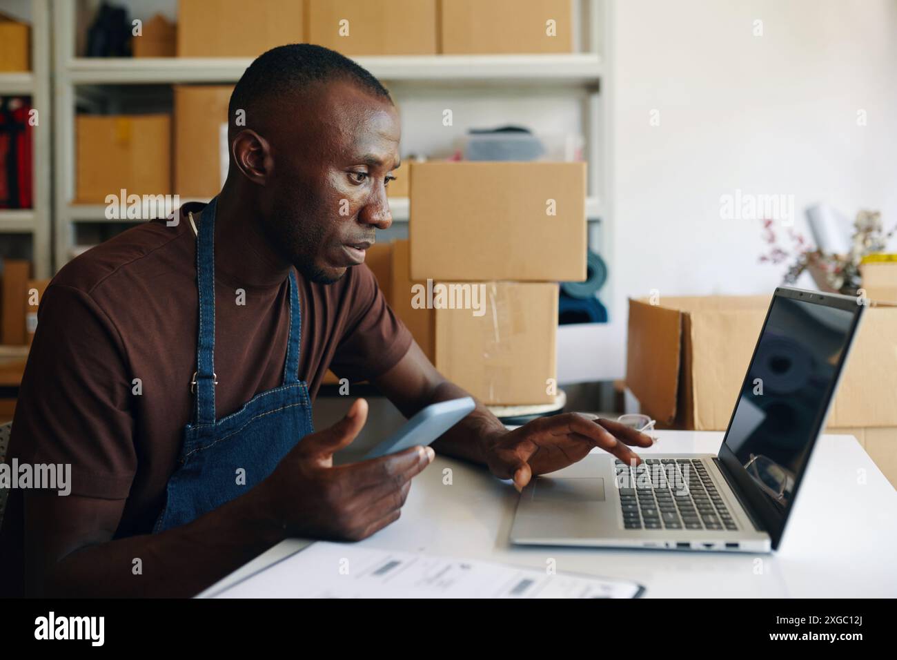Man Using Laptop In Storage Room Stock Photo