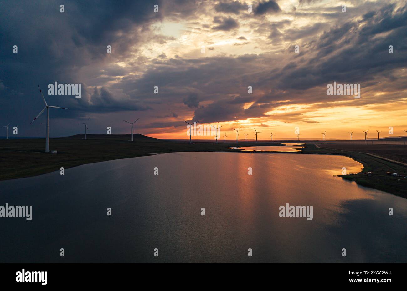 Wind turbines silhouette against sunset over lake Stock Photo - Alamy