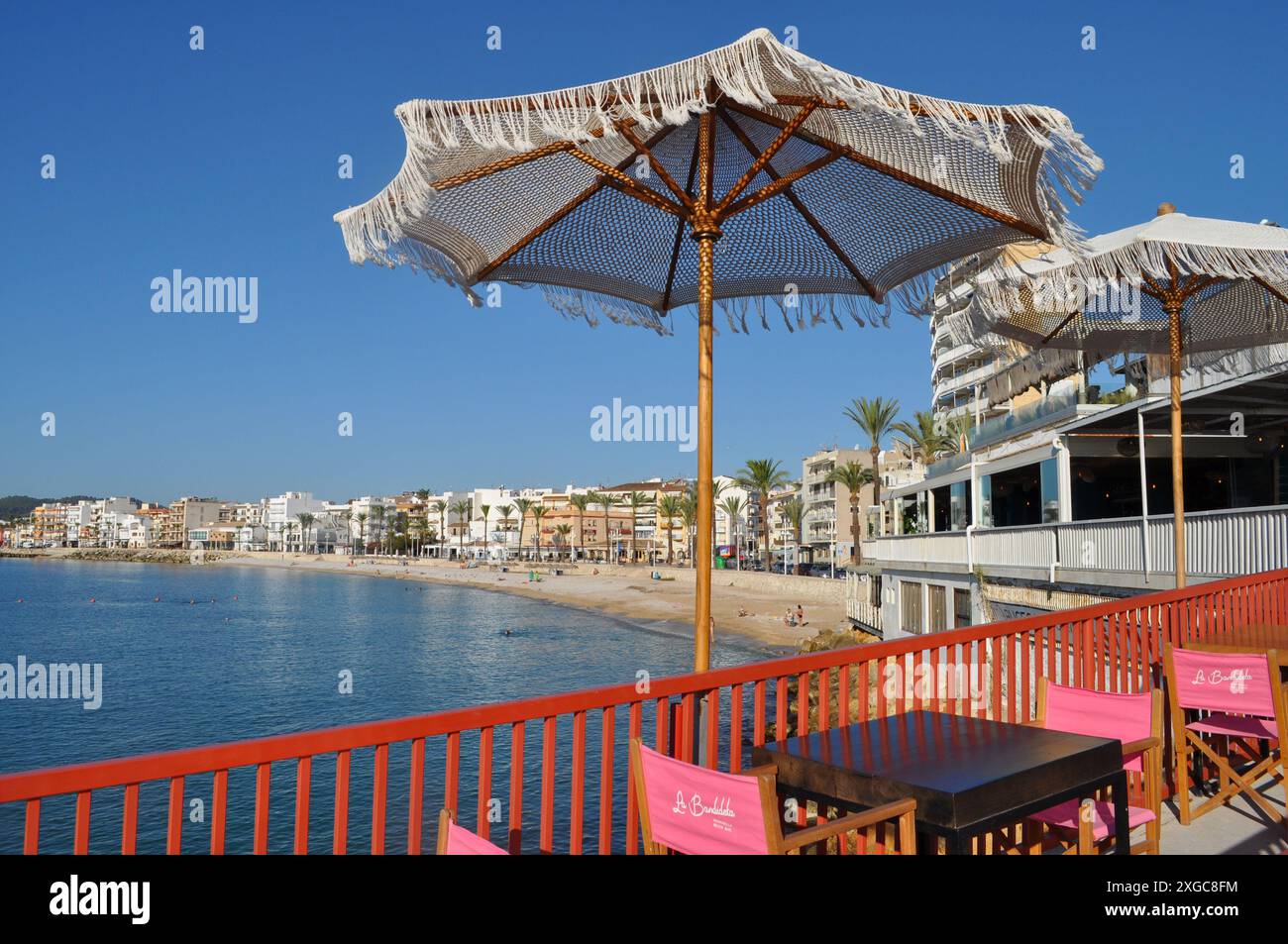 Outdoor cafe restaurant with sunshades in the port overlooking La Grava beach on teh Costa Blanca, Javea, Alicante Province, Spain Stock Photo