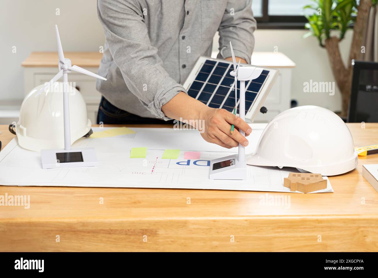 Desk of architects Solar Energy Powered Home Green for reduce global warming concept. Young businessman with wind turbine and solar panels at desk in Stock Photo