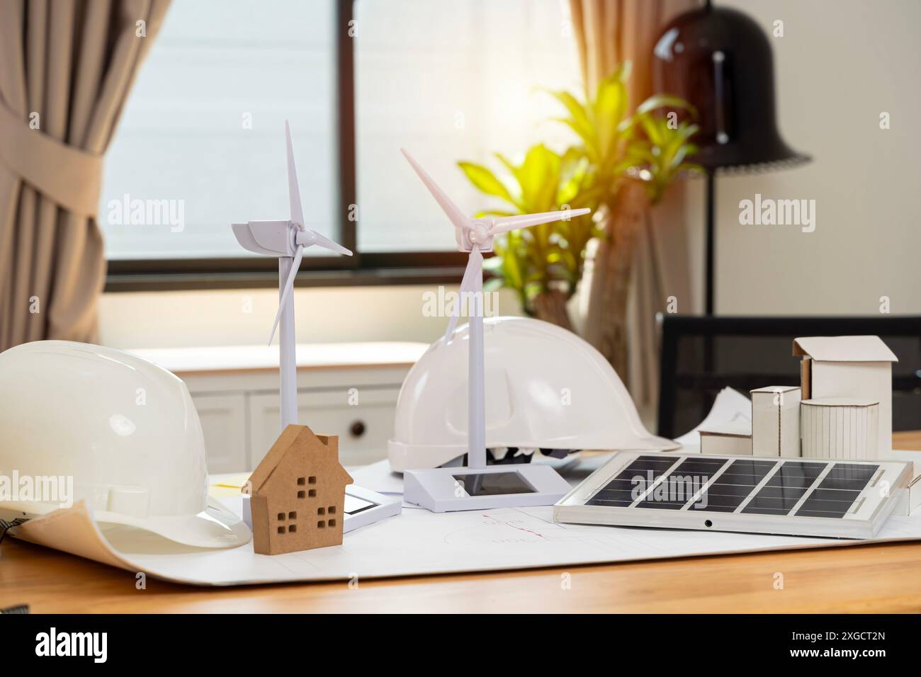 Wind turbines and solar cells. House on the table. Renewable energy concept. Portable solar panel and wind turbine model on engineer's desk. Stock Photo