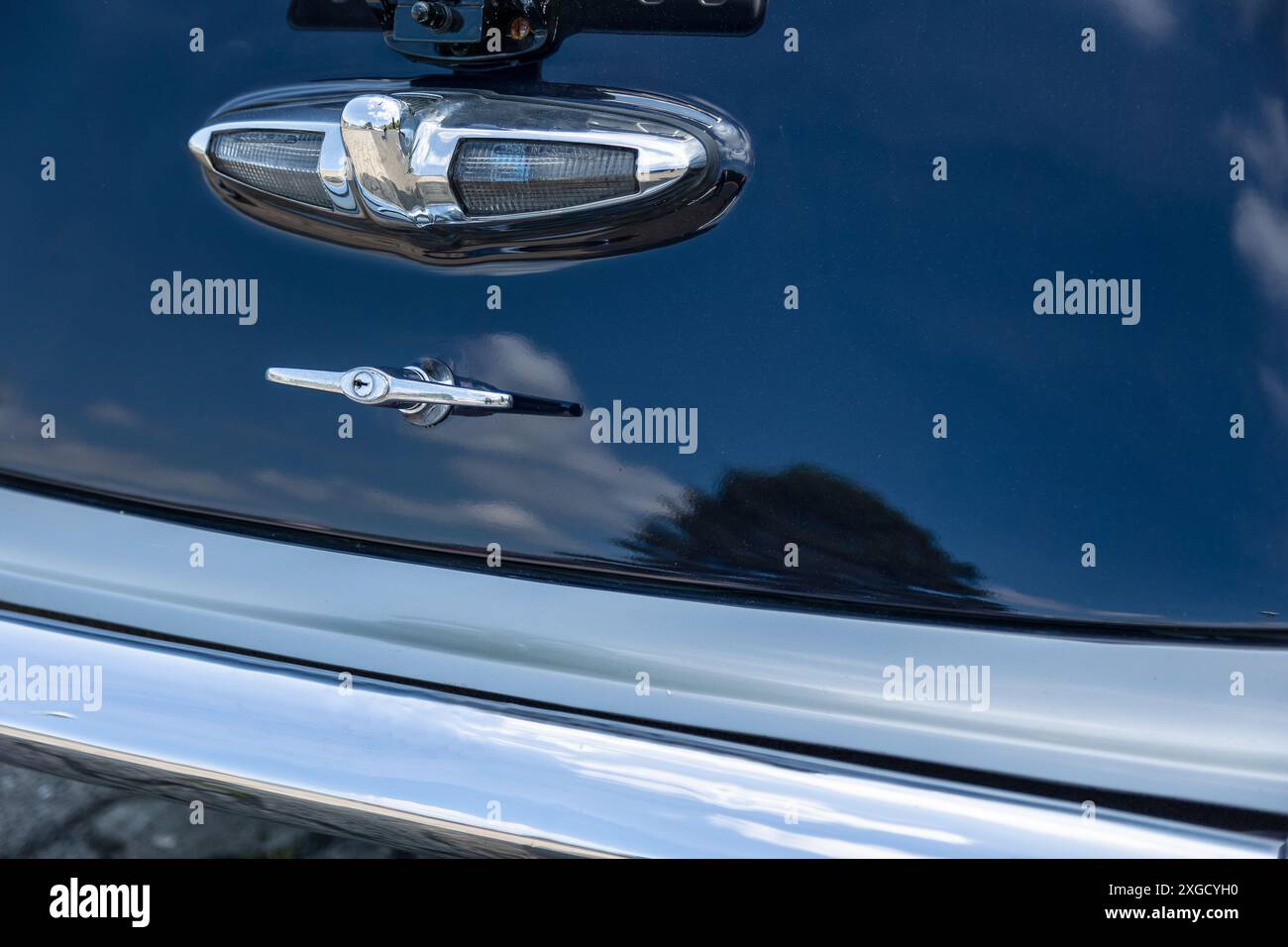 A close-up shot of a vintage car's rear trunk handle and bumper, showcasing the chrome detailing and classic design Stock Photo