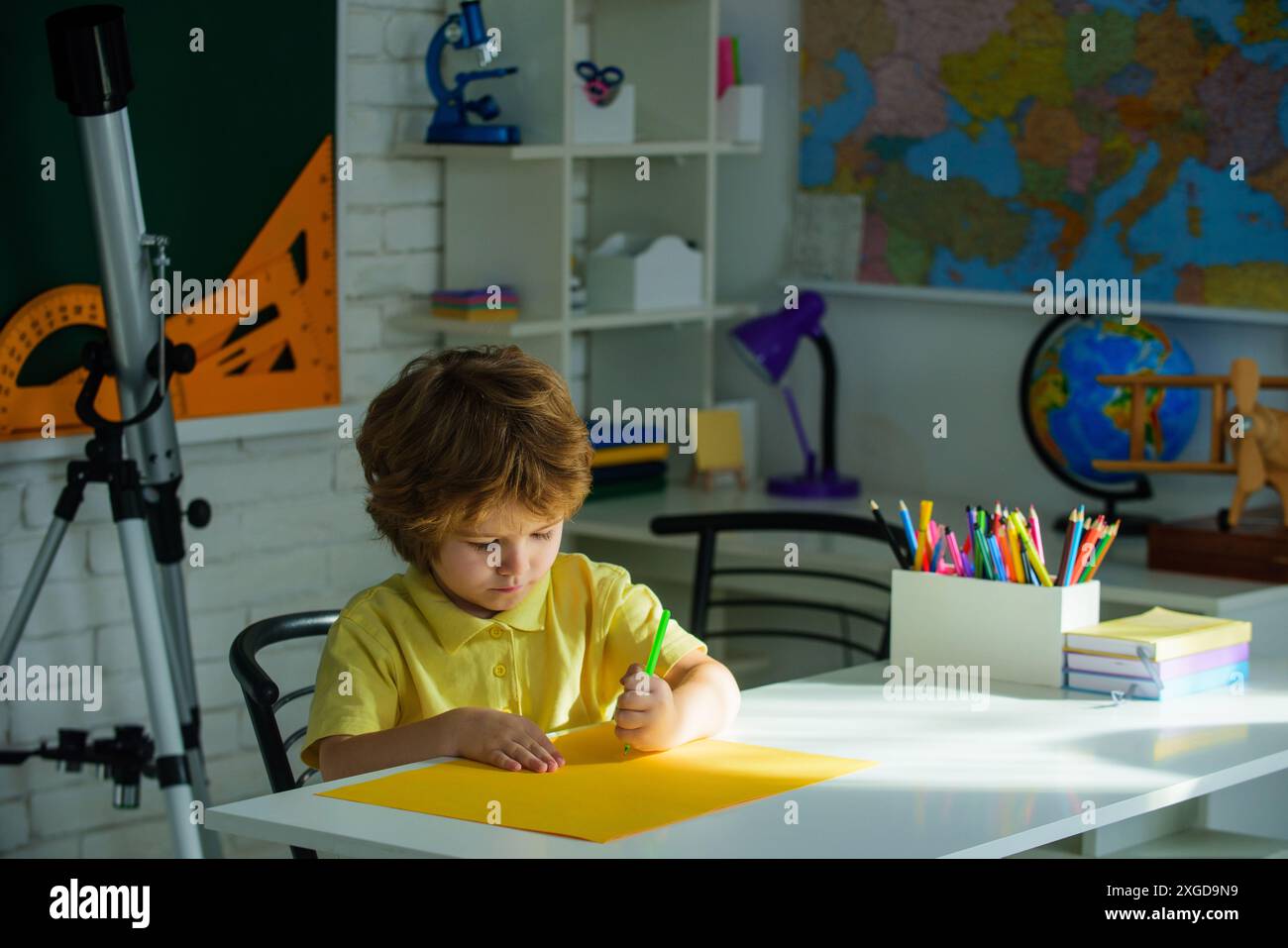 Back to school. Little schoolkid sitting at desk and writing. Child boy ...