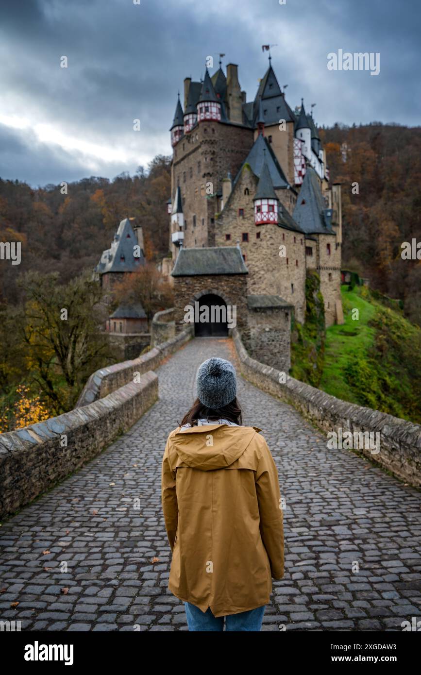 Back view of young woman with yellow jacket looking at Eltz medieval ...
